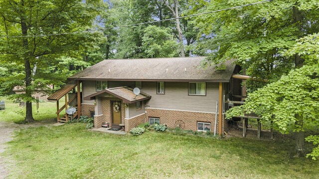 4424 Teal Ln, Newaygo, MI 49337 - view of front of home with a front lawn, a shingled roof, brick siding, and view of scattered trees