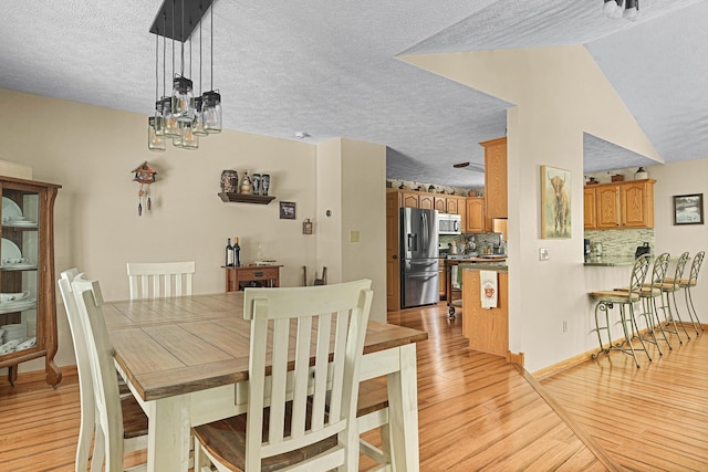 4792 Forest Vale Dr, Pierson, MI 49339 - dining area with light wood-style floors, a textured ceiling, and a chandelier