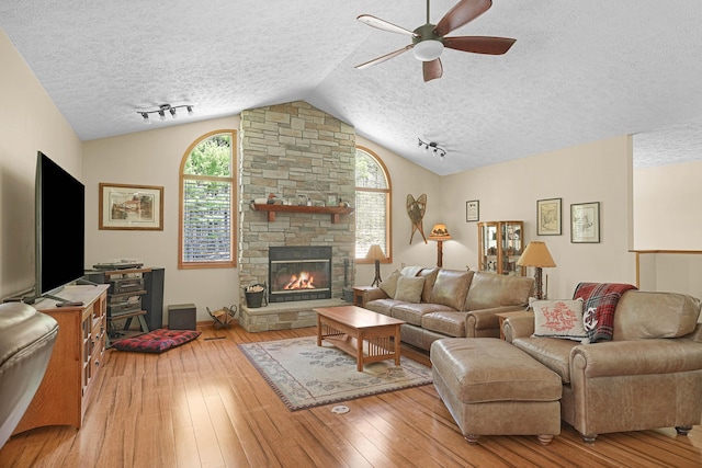 4792 Forest Vale Dr, Pierson, MI 49339 - living area with a textured ceiling, a ceiling fan, hardwood / wood-style flooring, vaulted ceiling, and a fireplace