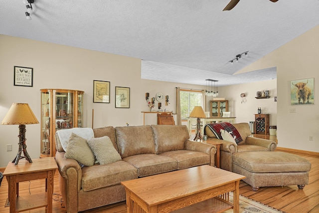 4792 Forest Vale Dr, Pierson, MI 49339 - living room featuring rail lighting, light wood-type flooring, a ceiling fan, a textured ceiling, and lofted ceiling