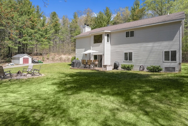 4792 Forest Vale Dr, Pierson, MI 49339 - back of house featuring an outdoor fire pit, a chimney, a yard, and an outbuilding