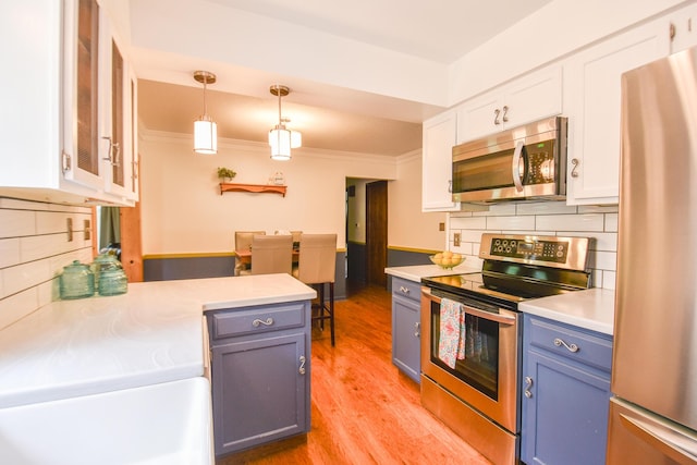72 Branch Ave, Coldwater, MI 49036 - kitchen featuring appliances with stainless steel finishes, blue cabinetry, white cabinetry, light countertops, and tasteful backsplash