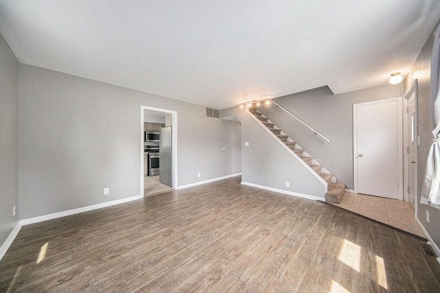 1836 W Argus Ct, Jackson, MI 49203 - unfurnished living room with wood finished floors and stairway