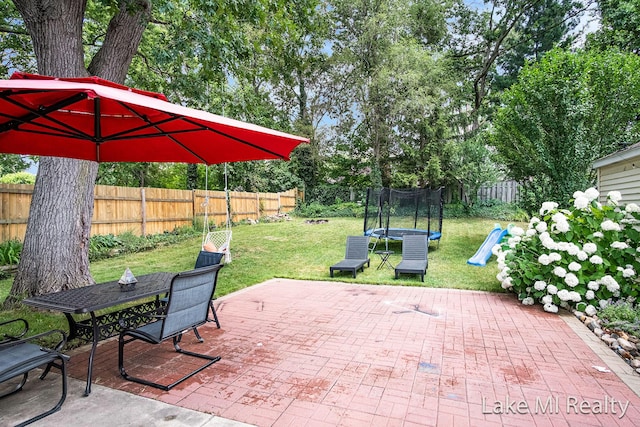 4128 Michael Ave SW, Wyoming, MI 49509 - fenced backyard with a trampoline, a patio area, outdoor dining area, and a playground