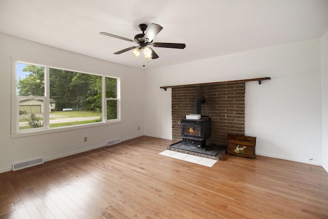 105 S Emerson Lake Rd, Branch, MI 49402 - unfurnished living room with a wood stove, light wood finished floors, and a ceiling fan