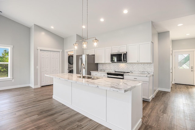 57860 James Dr, Three Rivers, MI 49093 - kitchen featuring stainless steel appliances, stacked washing machine and dryer, decorative backsplash, an island with sink, and wood finished floors
