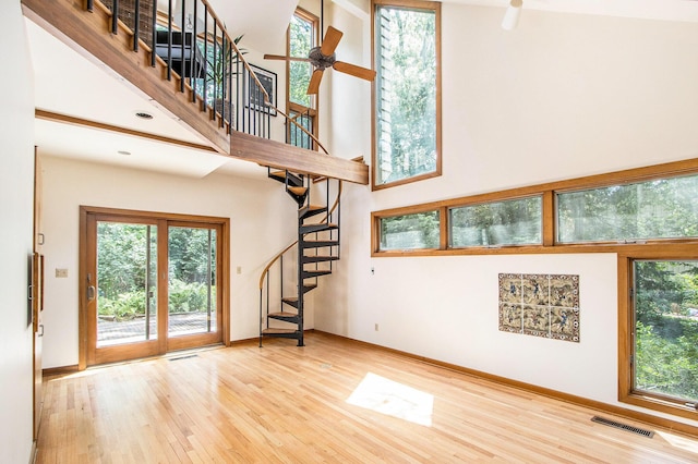 2425 University Ave, Kalamazoo, MI 49008 - unfurnished living room with stairs, wood finished floors, a ceiling fan, and a towering ceiling