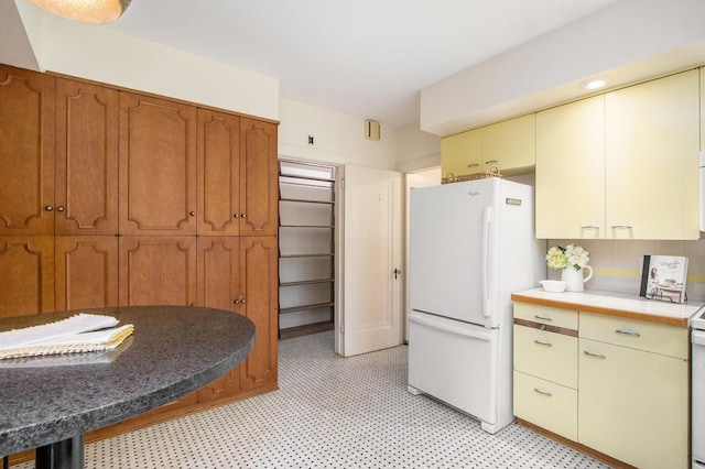 2425 University Ave, Kalamazoo, MI 49008 - kitchen with freestanding refrigerator, decorative backsplash, tile counters, brown cabinetry, and light floors