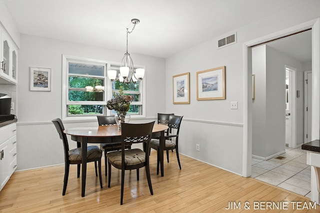 8518 146th Ave, West Olive, MI 49460 - dining space featuring light wood-style flooring, a chandelier, and a wainscoted wall