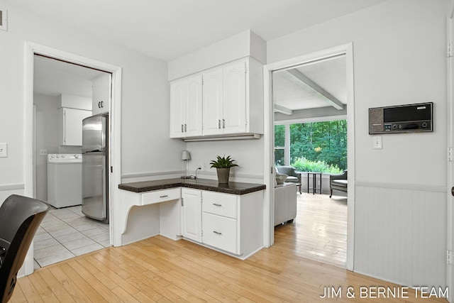 8518 146th Ave, West Olive, MI 49460 - kitchen featuring washer / dryer, white cabinets, freestanding refrigerator, dark countertops, and light wood-style flooring