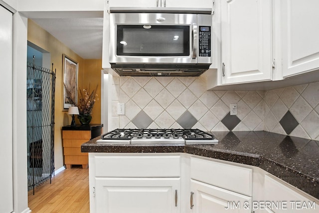 8518 146th Ave, West Olive, MI 49460 - kitchen with stainless steel appliances, white cabinetry, light wood-type flooring, and dark countertops