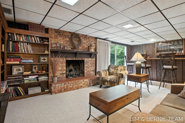 8518 146th Ave, West Olive, MI 49460 - living area featuring carpet floors, a paneled ceiling, a brick fireplace, and wood walls