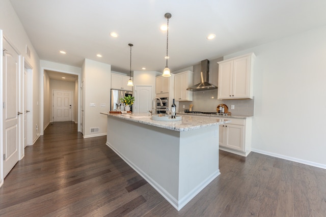 2763 Polson St, Ann Arbor, MI 48105 - kitchen featuring wall chimney range hood, appliances with stainless steel finishes, dark wood-type flooring, recessed lighting, and an island with sink