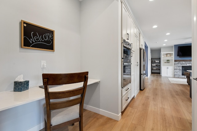46140 Finch St, Mattawan, MI 49071 - kitchen featuring stainless steel appliances, white cabinets, light wood-style flooring, recessed lighting, and a fireplace