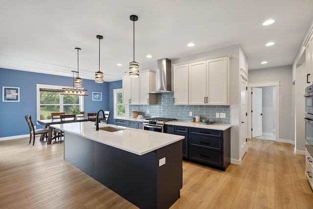 46140 Finch St, Mattawan, MI 49071 - kitchen featuring wall chimney exhaust hood, gas stove, light countertops, white cabinets, and decorative backsplash