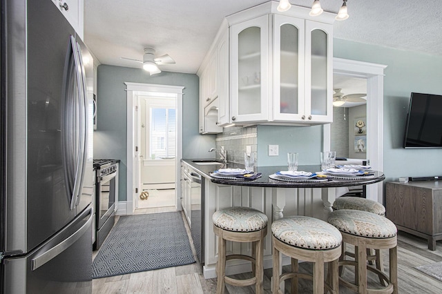 225 N Shore Dr Unit 302, South Haven, MI 49090 - kitchen featuring appliances with stainless steel finishes, a ceiling fan, white cabinetry, wood finished floors, and a breakfast bar area