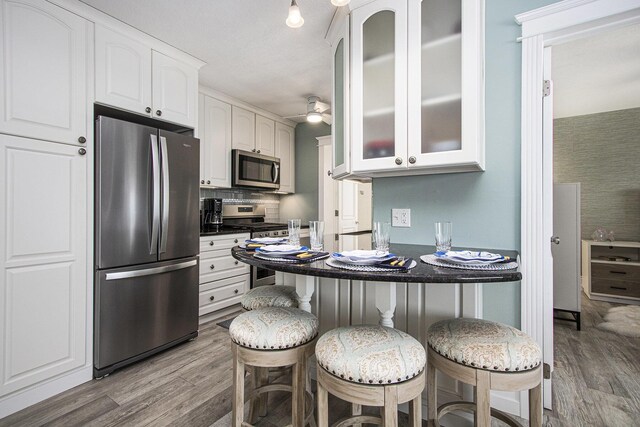 225 N Shore Dr Unit 302, South Haven, MI 49090 - kitchen with stainless steel appliances, white cabinets, light wood-type flooring, and a breakfast bar