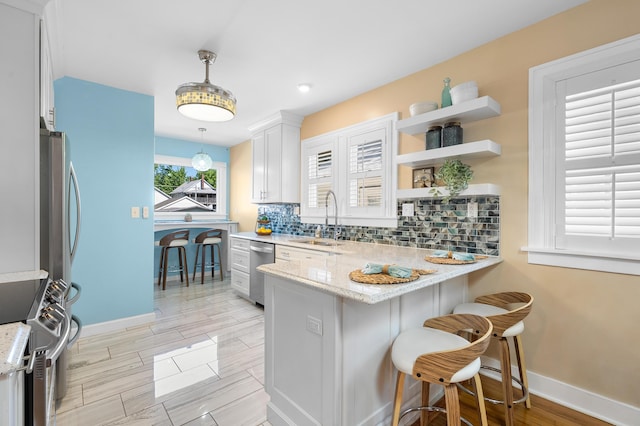 510 Wayne St, Saint Joseph, MI 49085 - kitchen featuring appliances with stainless steel finishes, tasteful backsplash, a peninsula, light stone counters, and wood finish floors
