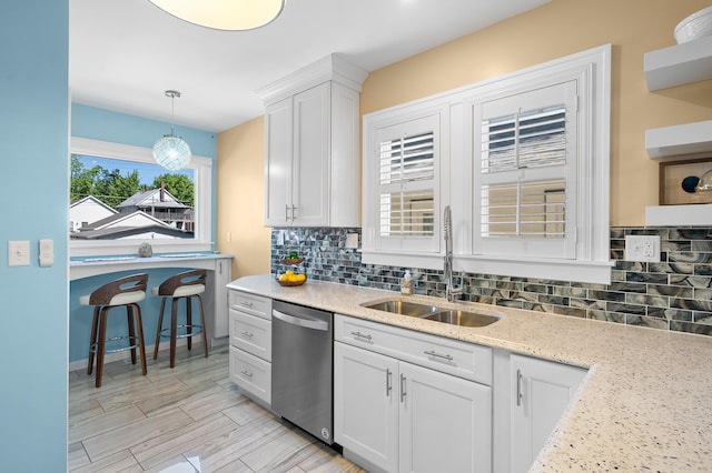 510 Wayne St, Saint Joseph, MI 49085 - kitchen with stainless steel dishwasher, white cabinets, backsplash, and decorative light fixtures