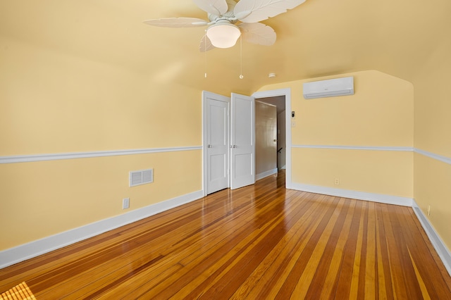 510 Wayne St, Saint Joseph, MI 49085 - empty room featuring an AC wall unit, hardwood / wood-style flooring, ceiling fan, and vaulted ceiling