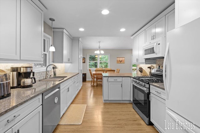 4712 Shank St NE, Rockford, MI 49341 - kitchen with appliances with stainless steel finishes, a peninsula, tasteful backsplash, light wood-type flooring, and recessed lighting