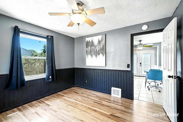 3725 Colby Ave SW, Wyoming, MI 49509 - spare room featuring wood finished floors, a wainscoted wall, a textured ceiling, ceiling fan, and a smoke detector