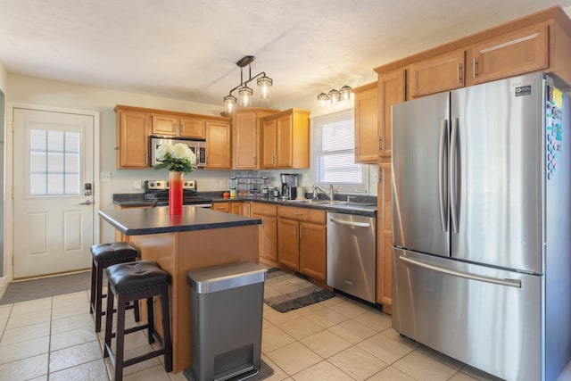 1762 Smyers Dr, Benton Harbor, MI 49022 - kitchen featuring appliances with stainless steel finishes, dark countertops, light tile patterned flooring, a center island, and a kitchen bar
