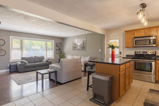 1762 Smyers Dr, Benton Harbor, MI 49022 - kitchen featuring stainless steel appliances, open floor plan, dark countertops, a breakfast bar area, and a kitchen island