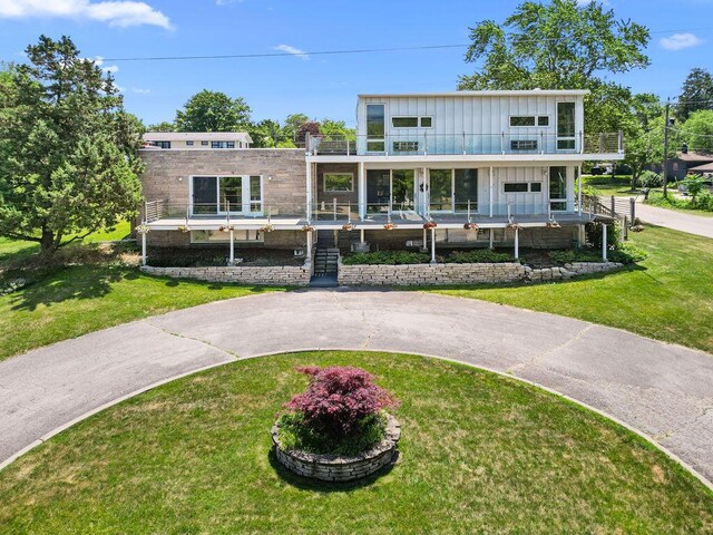 48002 Ridge Rd, New Buffalo, MI 49117 - view of front of house with a balcony, a front lawn, and board and batten siding