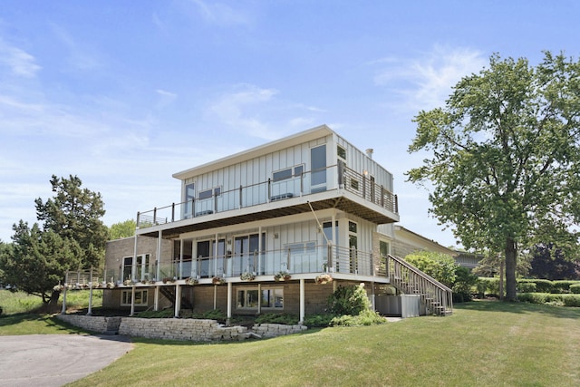 48002 Ridge Rd, New Buffalo, MI 49117 - rear view of house with a balcony, board and batten siding, and a lawn