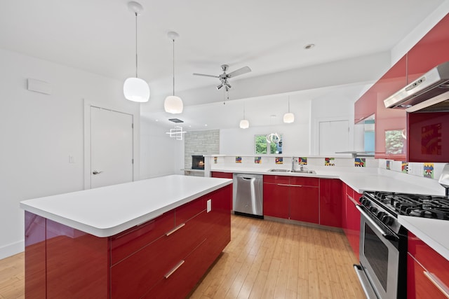 48002 Ridge Rd, New Buffalo, MI 49117 - kitchen with appliances with stainless steel finishes, red cabinetry, a ceiling fan, a fireplace, and light wood-style floors