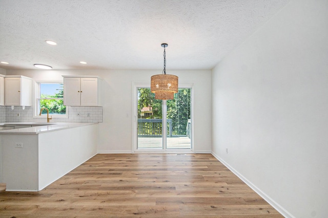 1882 Whistle Stop Dr SE, Grand Rapids, MI 49508 - kitchen featuring a textured ceiling, white cabinets, backsplash, light wood-type flooring, and light countertops