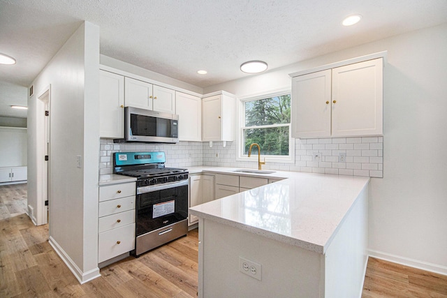 1882 Whistle Stop Dr SE, Grand Rapids, MI 49508 - kitchen with appliances with stainless steel finishes, a peninsula, light wood finished floors, white cabinets, and tasteful backsplash