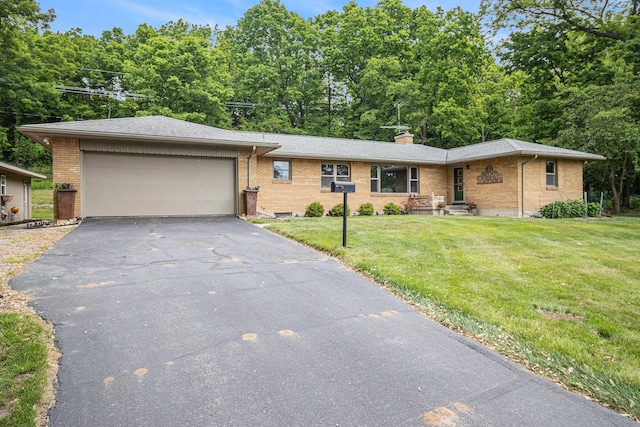 6667 W River Rd NE, Belmont, MI 49306 - view of front of home with asphalt driveway, brick siding, a garage, and a front yard