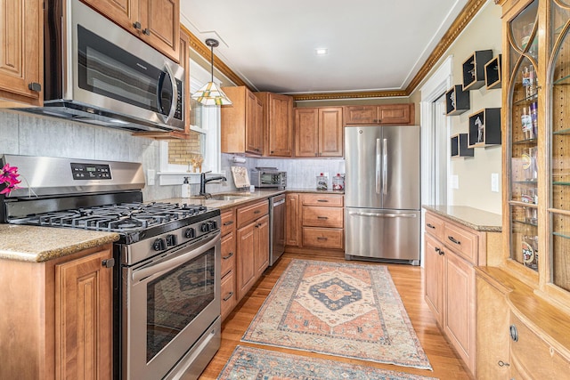 6667 W River Rd NE, Belmont, MI 49306 - kitchen featuring appliances with stainless steel finishes, light wood finished floors, decorative backsplash, pendant lighting, and ornamental molding