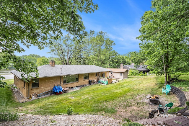 6667 W River Rd NE, Belmont, MI 49306 - back of property featuring a fire pit, a chimney, brick siding, and a yard