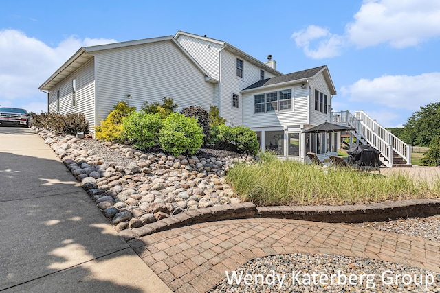 1033 Lumina Dr, Jenison, MI 49428 - rear view of property featuring a sunroom, stairs, driveway, and a chimney