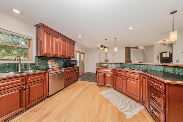 7532 Dell Rd, Saline, MI 48176 - kitchen featuring stainless steel appliances, light wood finished floors, dark countertops, tasteful backsplash, and decorative light fixtures