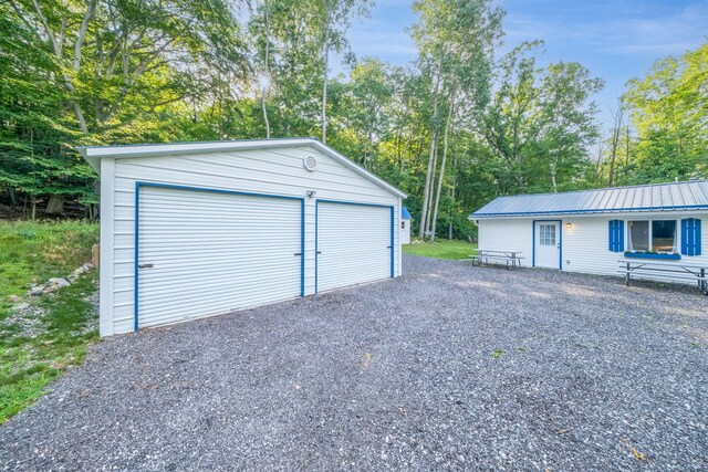 1051 Vallado Dr, Weidman, MI 48893 - detached garage featuring view of wooded area