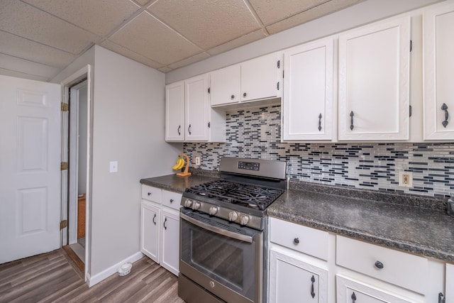 1051 Vallado Dr, Weidman, MI 48893 - kitchen with stainless steel range with gas cooktop, dark countertops, wood finished floors, white cabinets, and a drop ceiling