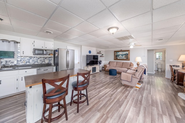 1051 Vallado Dr, Weidman, MI 48893 - kitchen with appliances with stainless steel finishes, a paneled ceiling, white cabinets, open floor plan, and light wood-style floors