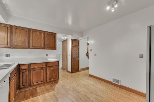 2145 Steeplechase Dr, Ann Arbor, MI 48103 - kitchen featuring white dishwasher, brown cabinets, light wood-style floors, and light countertops