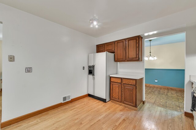 2145 Steeplechase Dr, Ann Arbor, MI 48103 - kitchen featuring white refrigerator with ice dispenser, brown cabinetry, light wood-style floors, light countertops, and a chandelier
