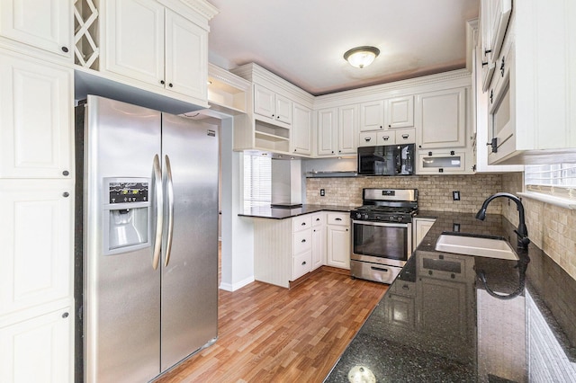 7400 Willow Creek Dr, Ypsilanti, MI 48197 - kitchen featuring stainless steel appliances, light wood-type flooring, white cabinetry, tasteful backsplash, and dark stone countertops