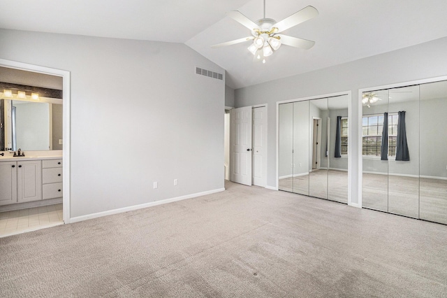 7400 Willow Creek Dr, Ypsilanti, MI 48197 - unfurnished bedroom with multiple closets, light carpet, vaulted ceiling, ensuite bath, and ceiling fan