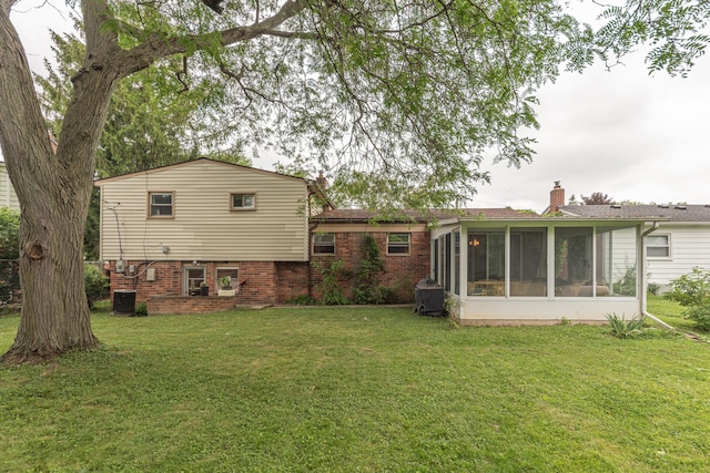 2707 Brandywine Dr, Ann Arbor, MI 48104 - rear view of house featuring a sunroom, a lawn, brick siding, and a chimney
