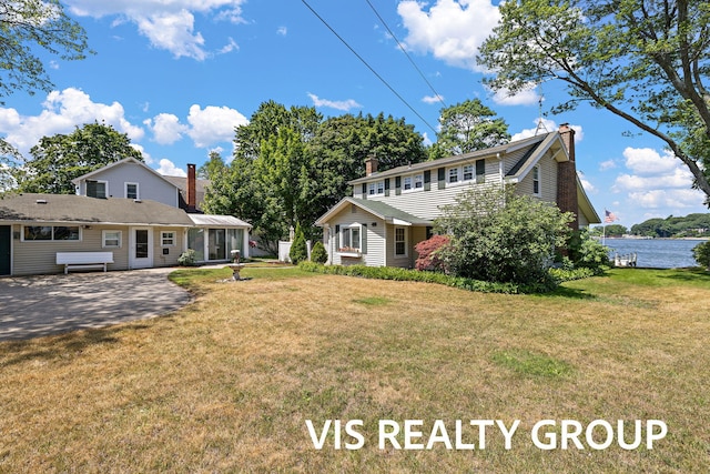 537 Buena Vista Dr, Spring Lake, MI 49456 - view of front of property with a chimney, a front lawn, a sunroom, and a water view