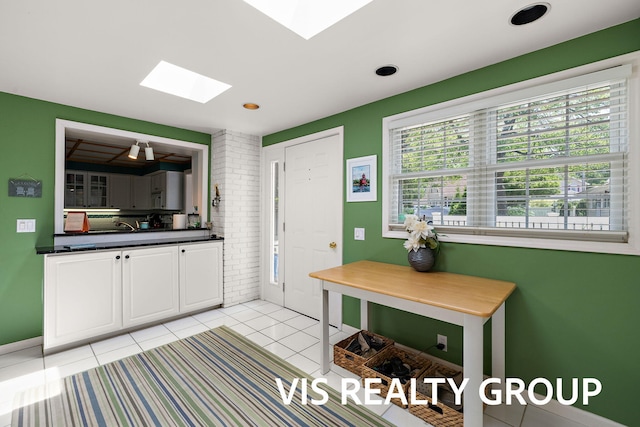 537 Buena Vista Dr, Spring Lake, MI 49456 - kitchen with a skylight, white cabinetry, dark countertops, and light tile patterned floors
