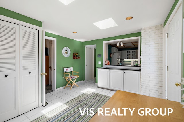 537 Buena Vista Dr, Spring Lake, MI 49456 - kitchen featuring a skylight, light tile patterned floors, refrigerator with ice dispenser, dark countertops, and white cabinetry