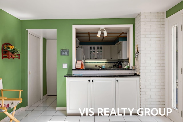 537 Buena Vista Dr, Spring Lake, MI 49456 - kitchen with dark countertops, freestanding refrigerator, glass insert cabinets, decorative backsplash, and light tile patterned floors